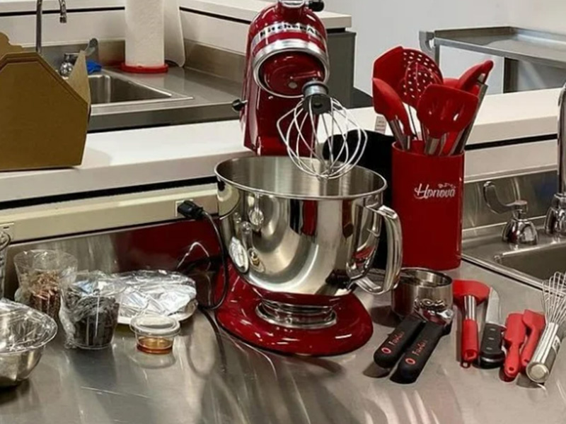 Red Kitchen Aid mixer and other baking tools on stainless steel table